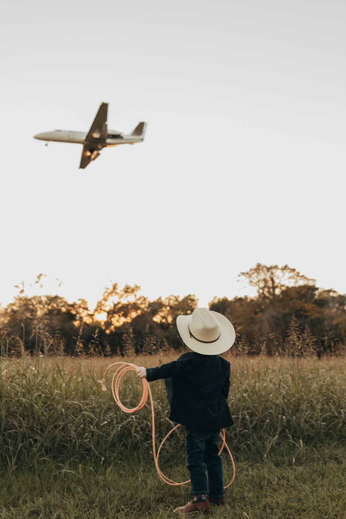little boy roping an airplane in a field for Houston family photographer, ally's photography