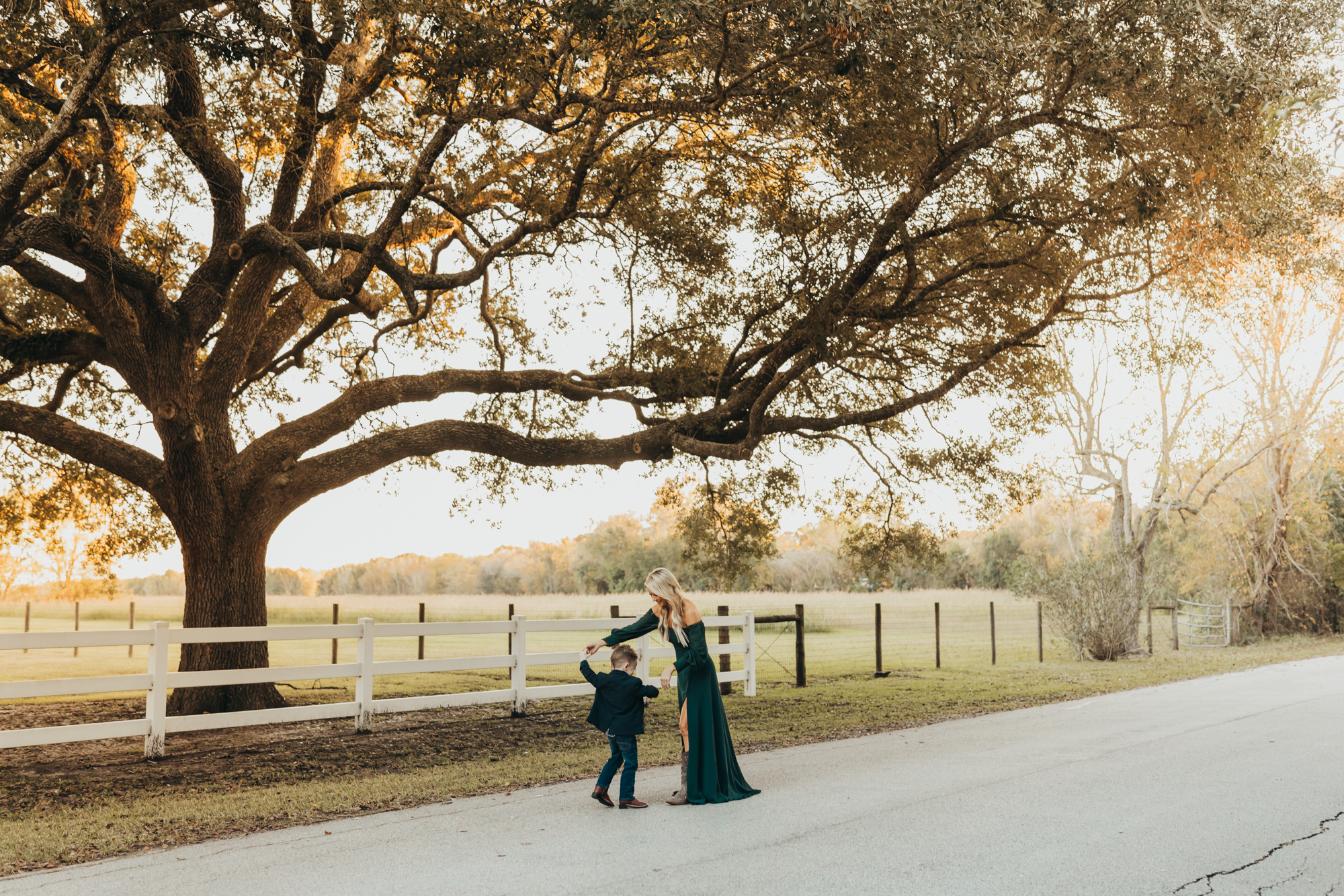 Mom and son dance in the middle of the street under old oak trees in Houston, during golden hour.