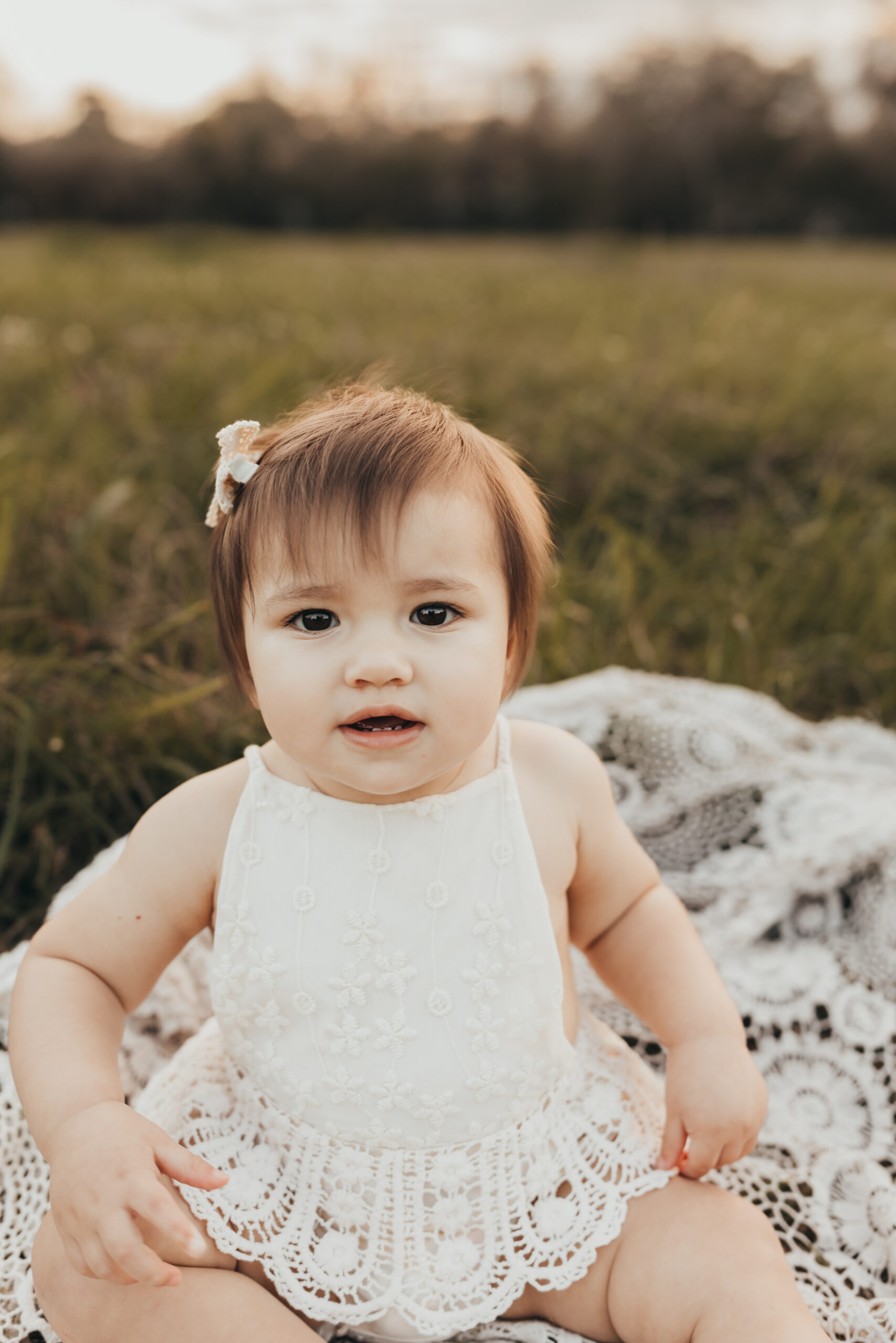 Little girl sitting on a blanket for her one year milestone session wearing boho outfits inspired at Houston Baby Stores
