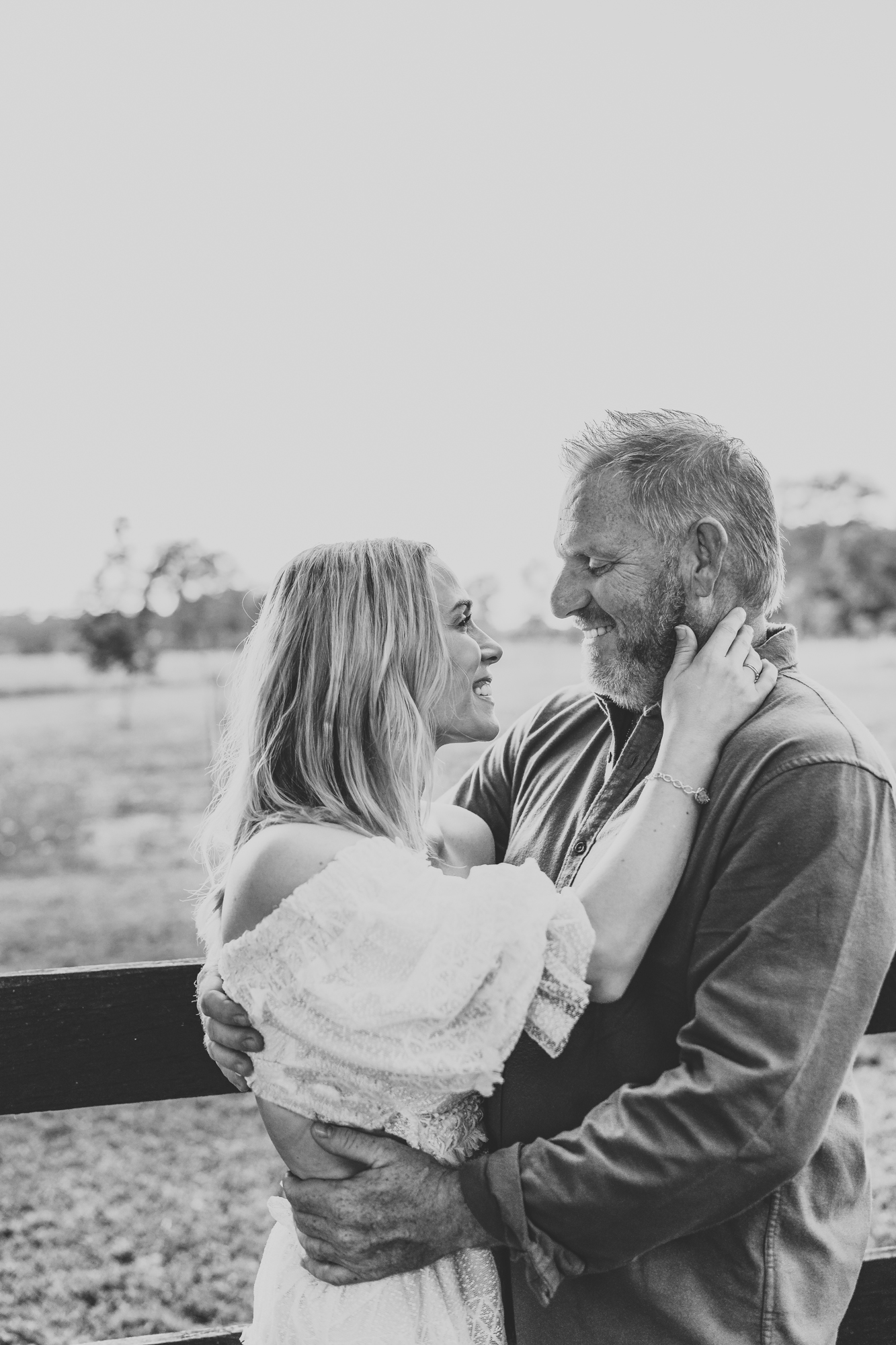 black and white image of a man holding his wife during a family portrait session, excitedly planning a romantic getaway in Texas.