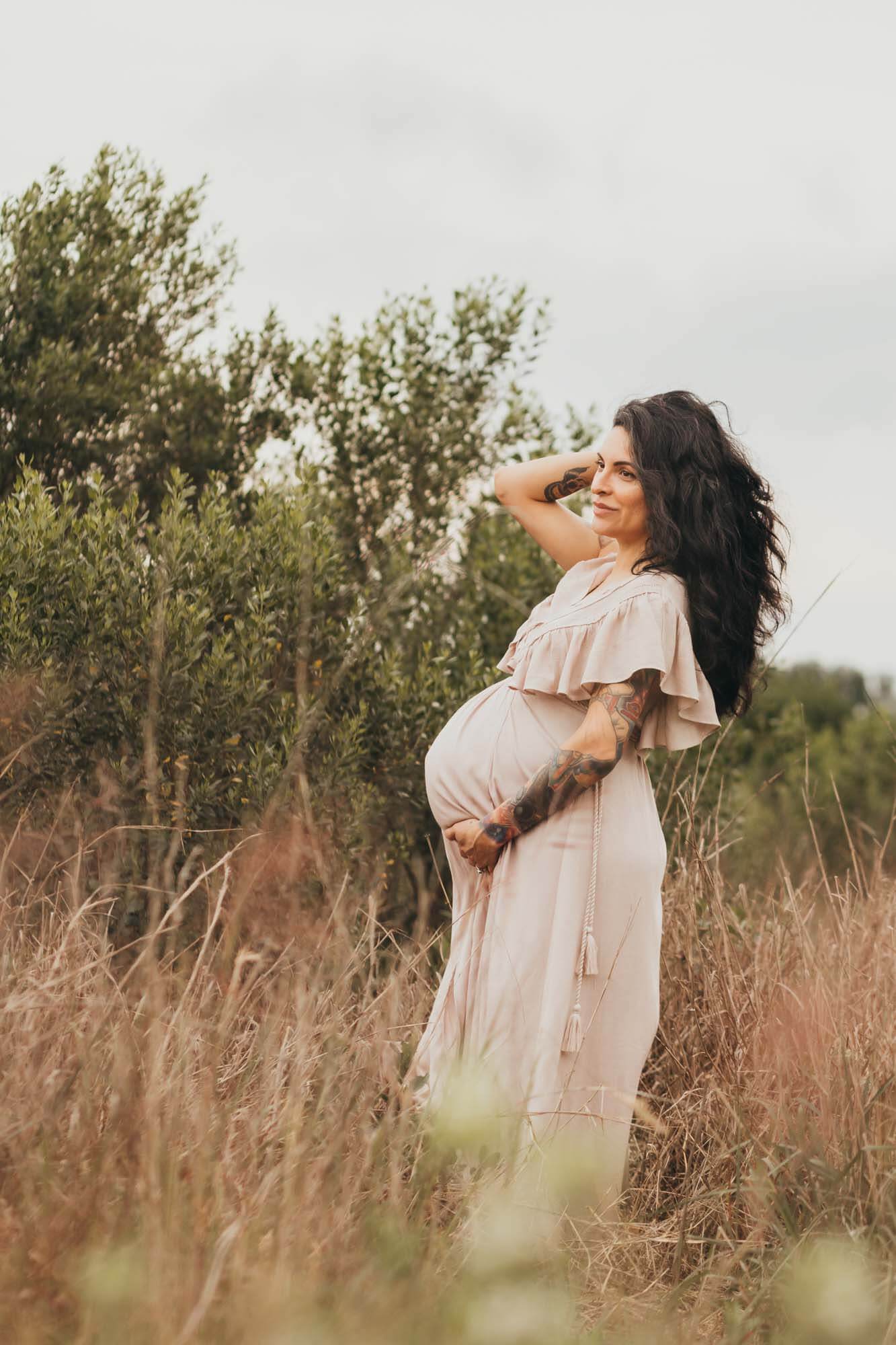 expectant mom caresses her belly while running her hands through her hair.