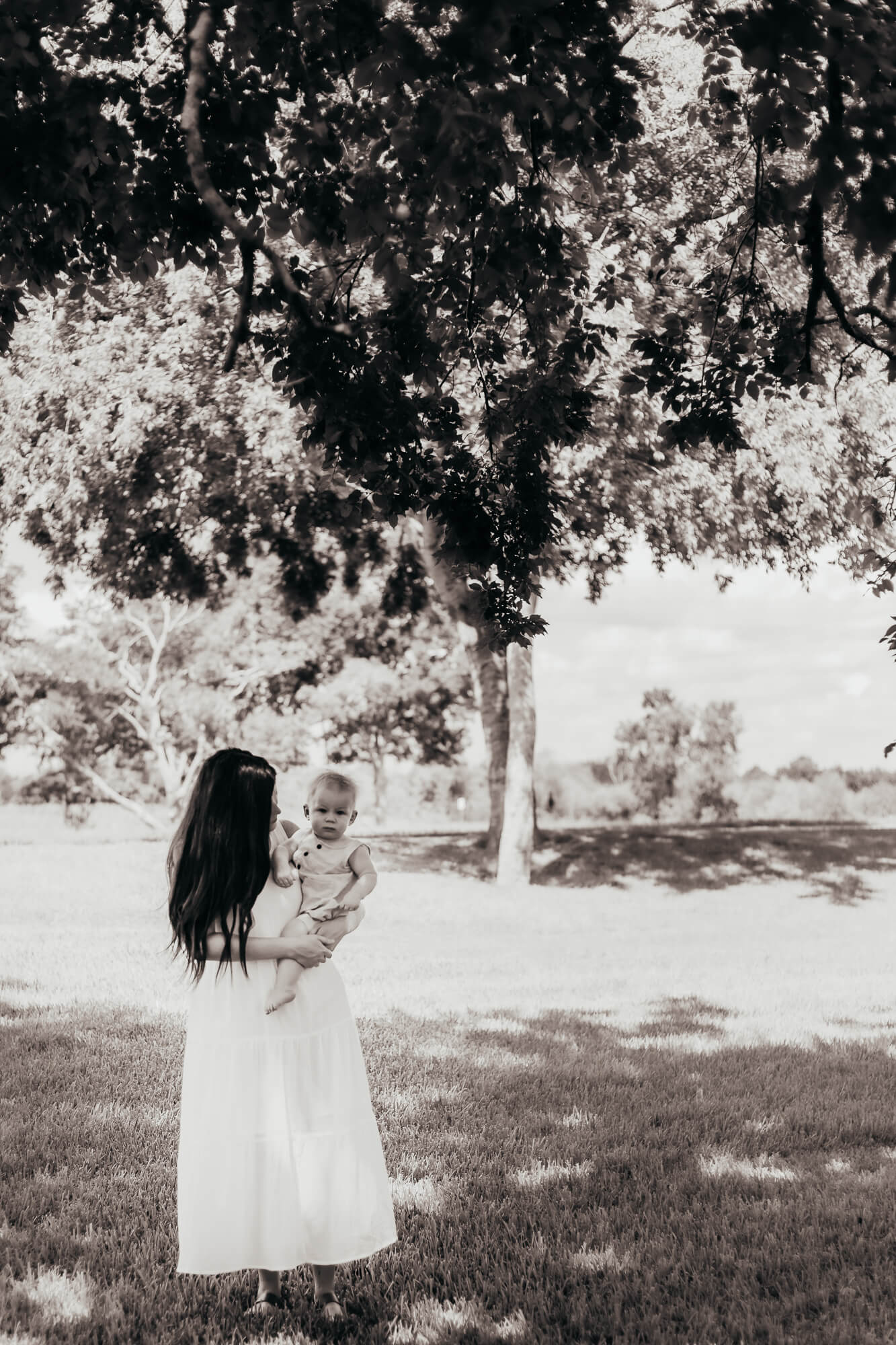 Little boy being held by his mom under a tree in Pearland, Texas. Photo taken by Ally's Photography.