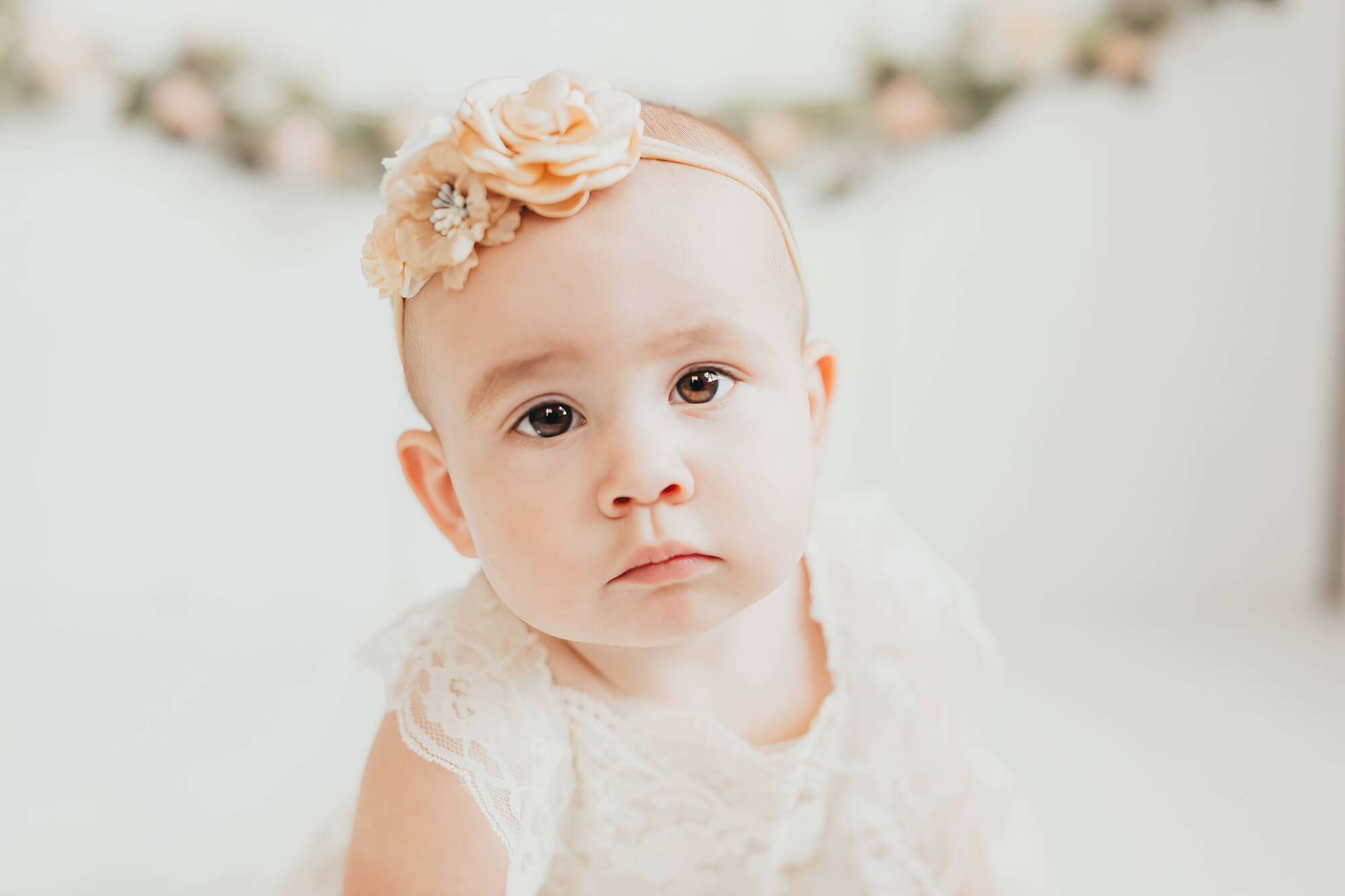 Many women are looking for Houston Water birth options. Little girl wearing a floral bow and lace romper for her first birthday photos with Ally's Photography.
